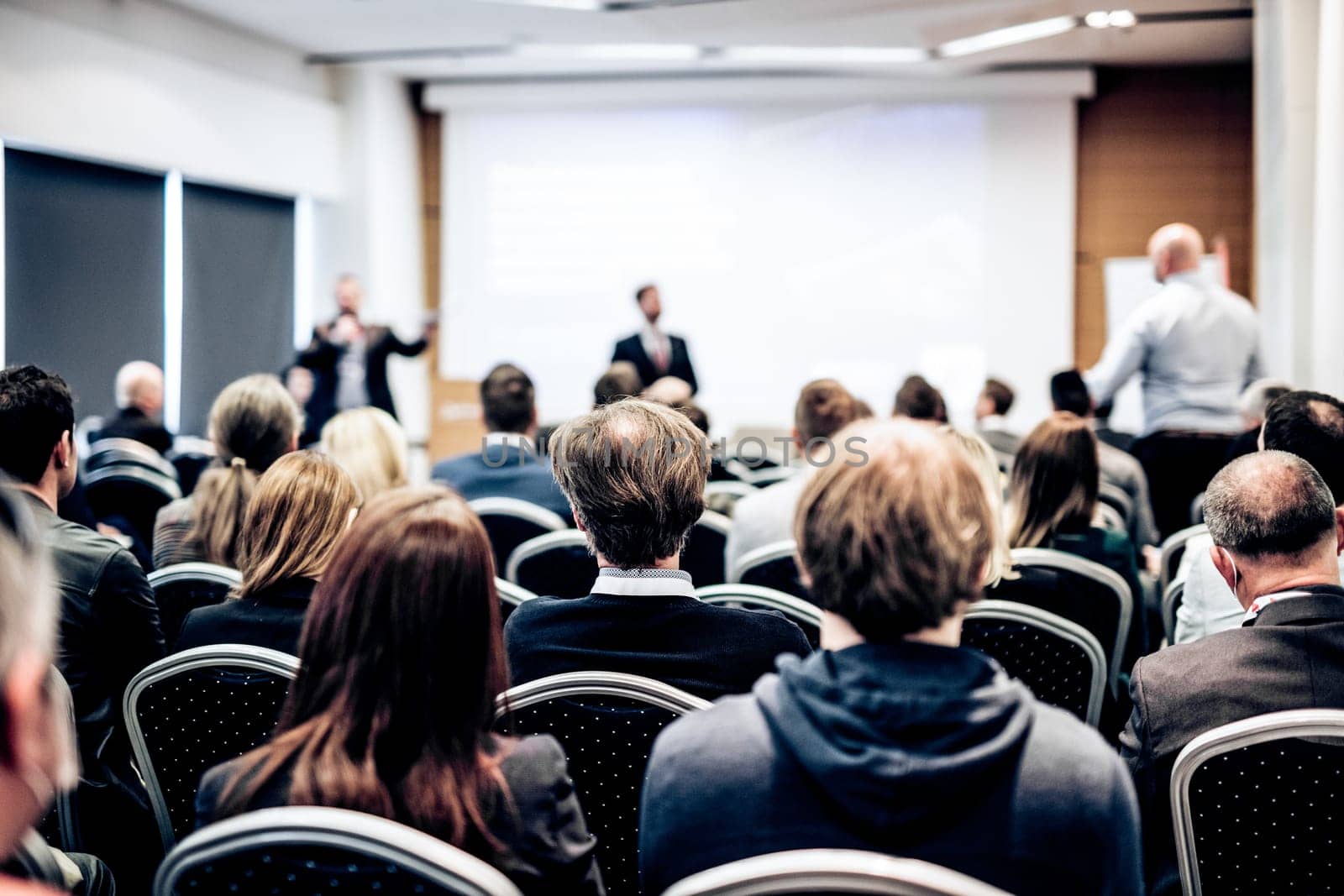 I have a question. Group of business people sitting at the chairs in conference hall. Businessman standing up asking a question. Conference and Presentation. Business and Entrepreneurship.