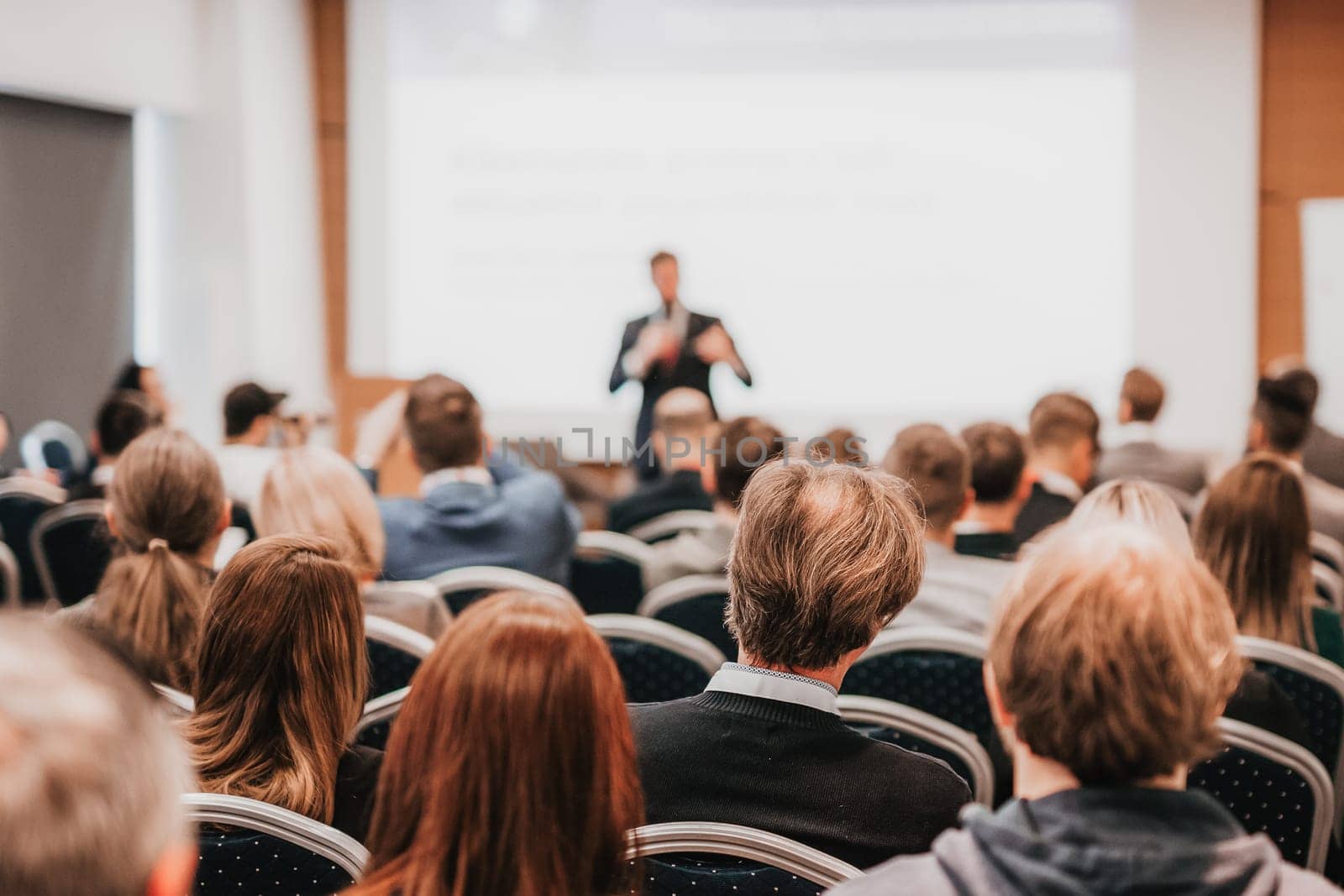 Speaker giving a talk in conference hall at business event. Rear view of unrecognizable people in audience at the conference hall. Business and entrepreneurship concept