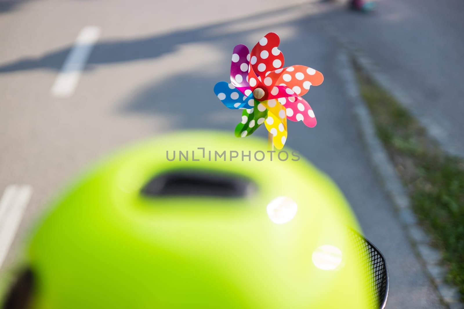 Colorful pinwheel attached to bicycle basket to entertain toddler child riding on front child seat on bike in summer