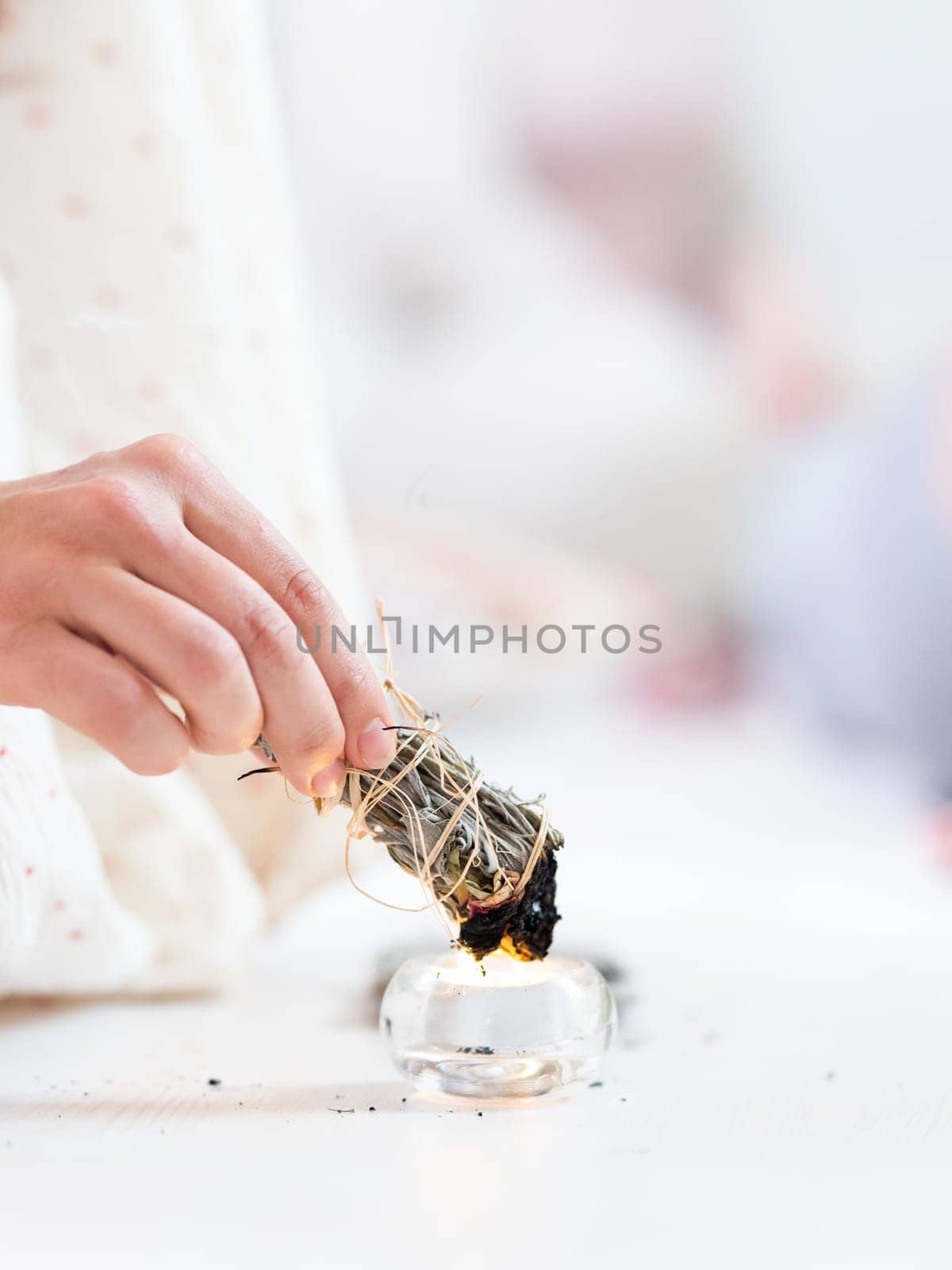 Woman lighting a smudge kit with herbal stick. Natural elements for cleansing environment from negative energy, adding positive vibes. Spriritual wellness practices
