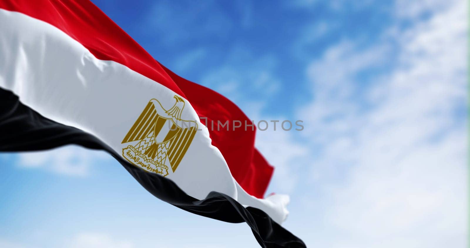 National flag of Egypt waving in the wind on a clear day. Horizontal red, white and black bands. Egyptian eagle emblem centered in white band. 3d illustration render. Fluttering fabric