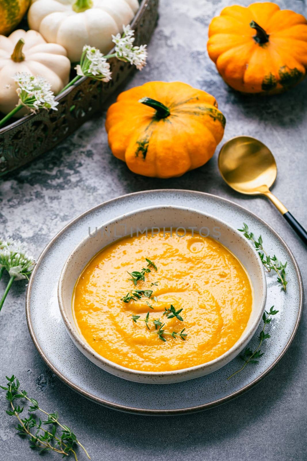 Pumpkin soup with pumpkin seeds served in bowl on rustic kitchen table