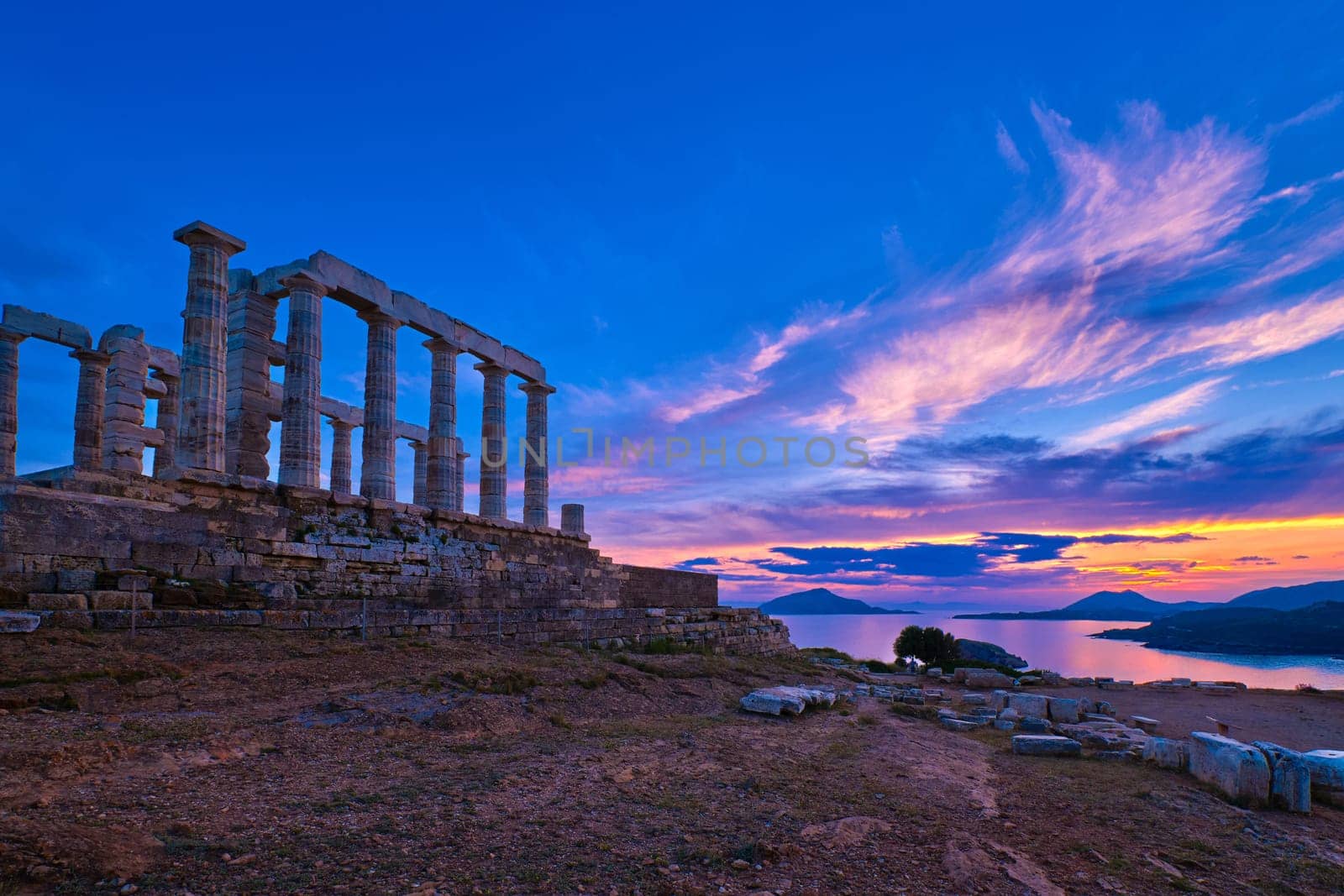 Beautiful sunset sky and ancient ruins of temple of Poseidon, cape Sounio, Aegean sea coast, Greece. Travel destination of Athens area, important center of ancient Greek religion for Olympian Greek mythology, god of the sea and earthquakes,