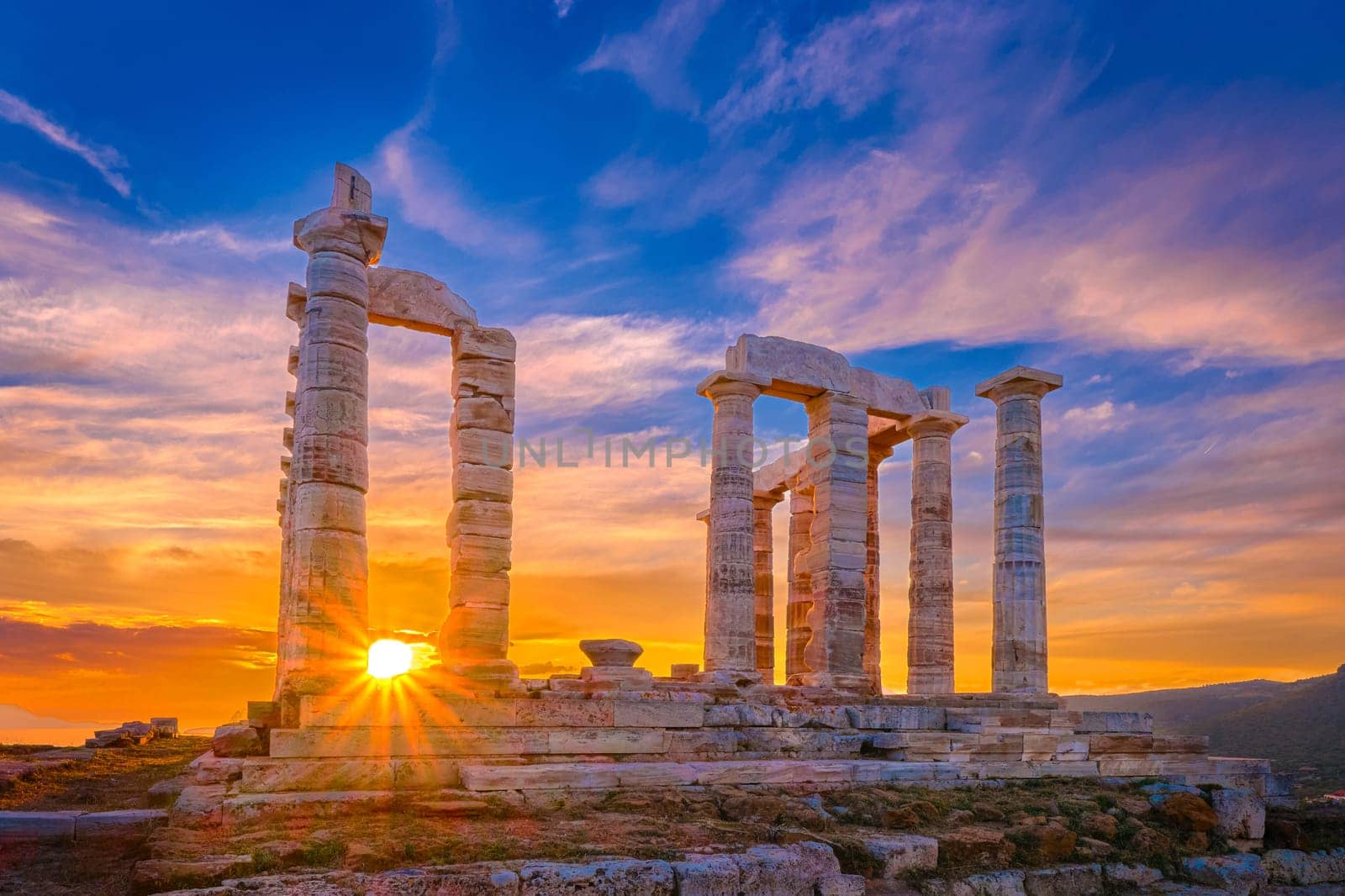 Beautiful sunset sky and ancient ruins of temple of Poseidon, cape Sounio, Aegean sea coast, Greece. Travel destination of Athens area, important center of ancient Greek religion for Olympian Greek mythology, god of the sea and earthquakes,