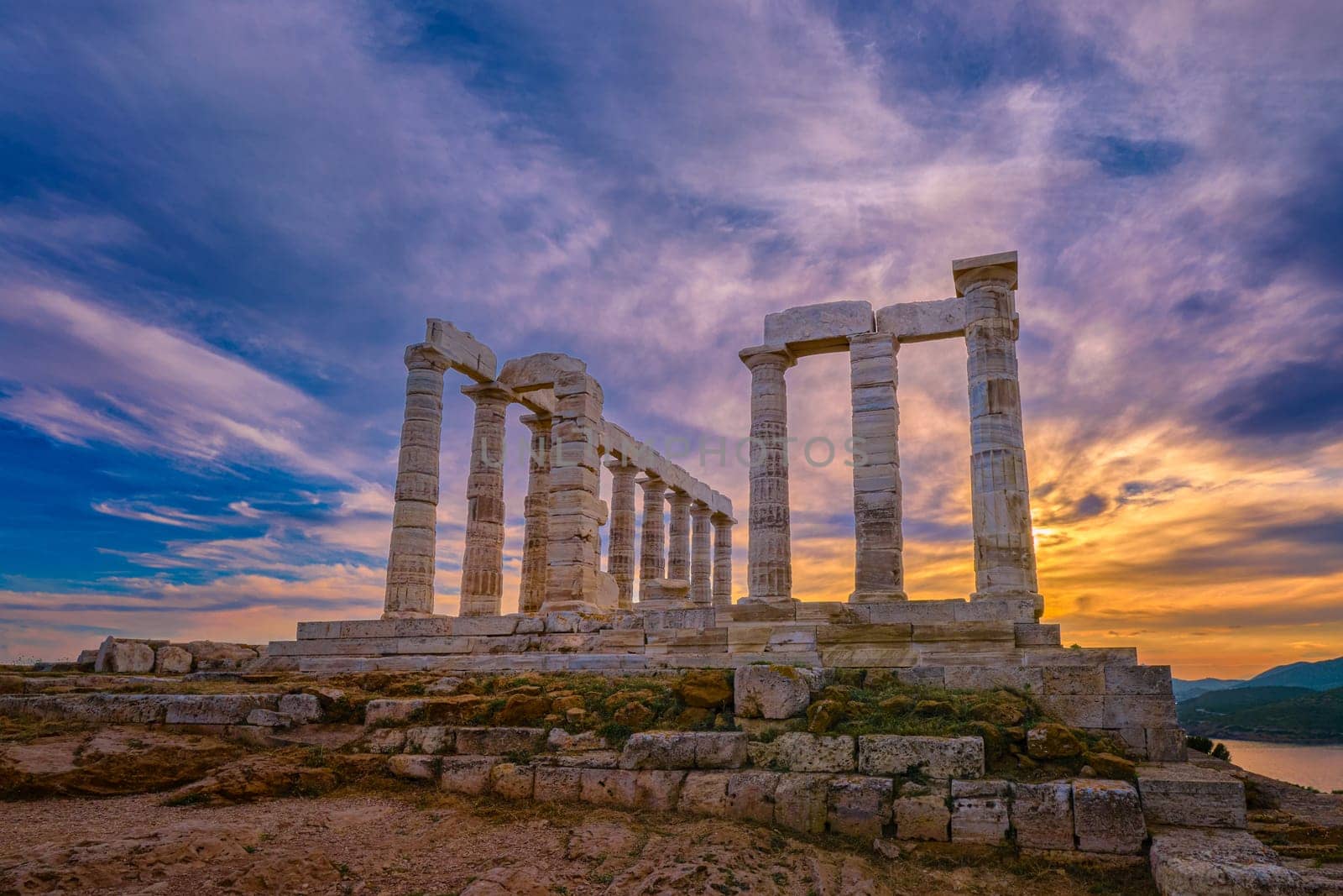 Beautiful sunset sky and ancient ruins of temple of Poseidon, cape Sounio, Aegean sea coast, Greece. Travel destination of Athens area, important center of ancient Greek religion for Olympian Greek mythology, god of the sea and earthquakes,