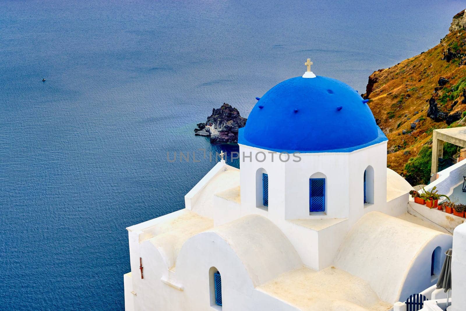 Beautiful view of Santorini island village or town, Greece. Whitewashed houses and churches, blue dome, sea waters of caldera bay, rough cliffs. Famous tourist attraction, romantic travel destination, summer vacations.