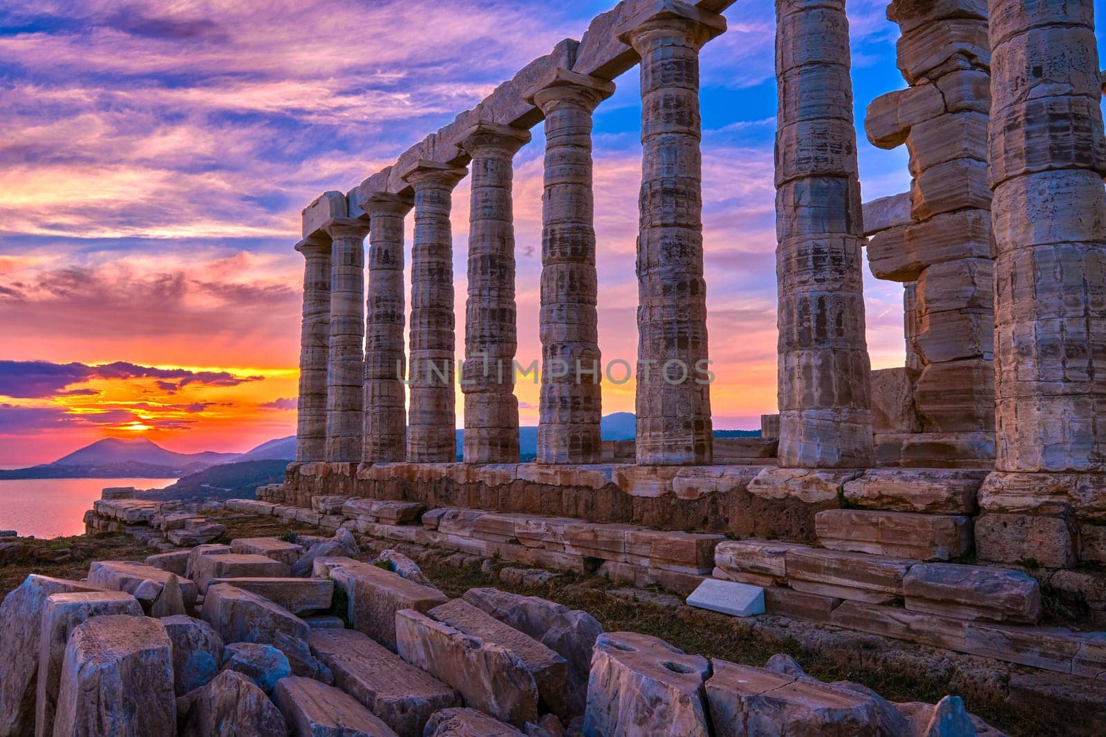 Beautiful sunset sky and ancient ruins of temple of Poseidon, cape Sounio, Aegean sea coast, Greece. Travel destination of Athens area, important center of ancient Greek religion for Olympian Greek mythology, god of the sea and earthquakes,