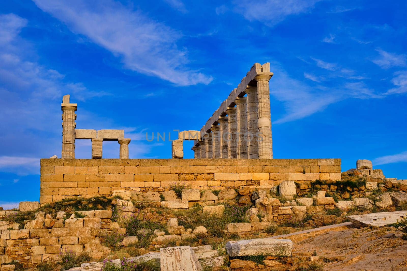 Beautiful sunset sky and ancient ruins of temple of Poseidon, cape Sounio, Aegean sea coast, Greece. Travel destination of Athens area, important center of ancient Greek religion for Olympian Greek mythology, god of the sea and earthquakes,