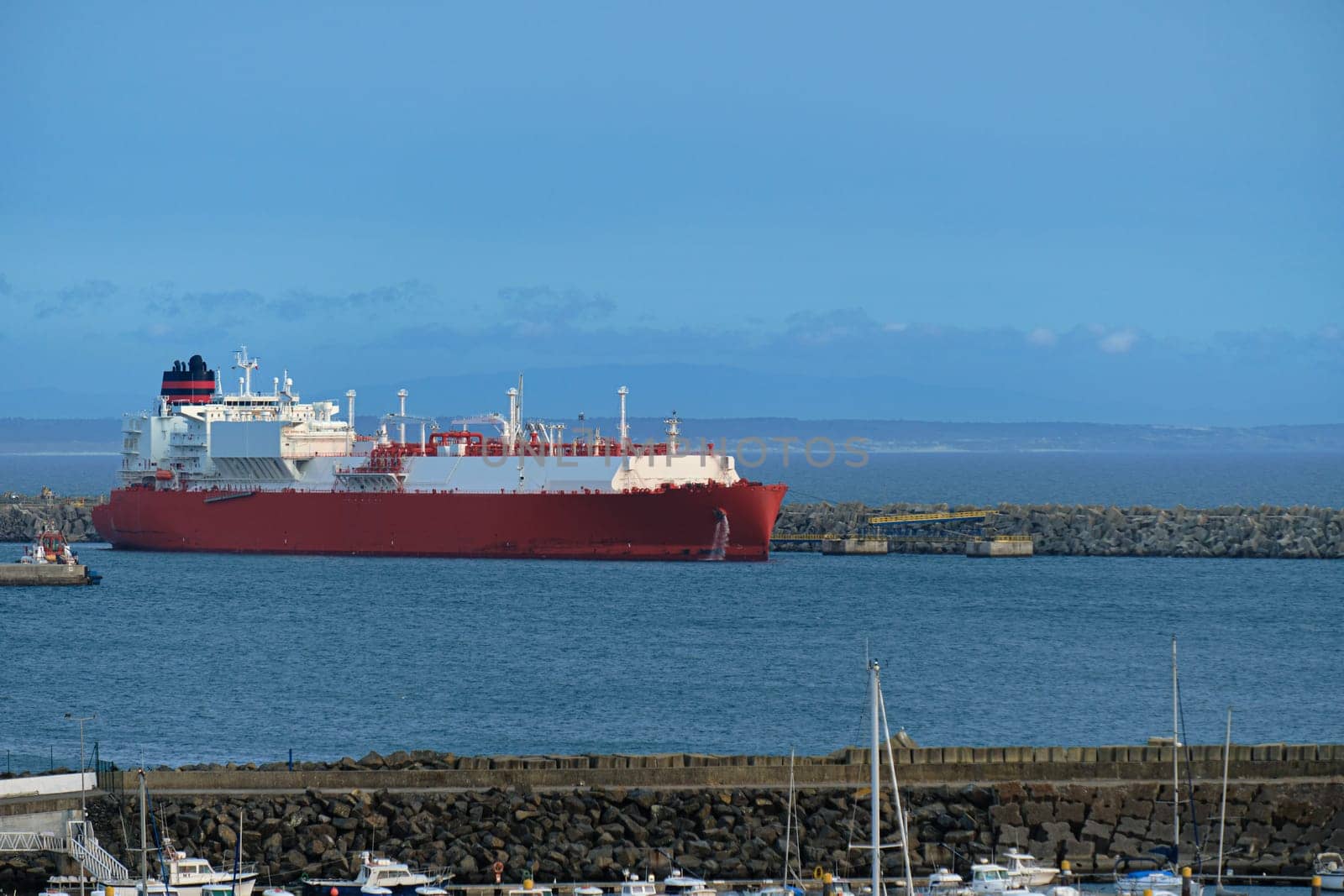 LNG or liquified natural gas carrier moored by industrial pier on hazy evening. Alternative gas supply, commercial freight, energy crisis, regasification, diversification, fuel and energy generation.