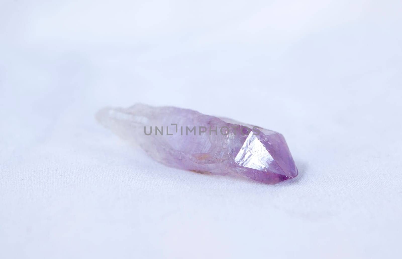 Brazilian amethyst fragment. Isolated over white fabric cloth