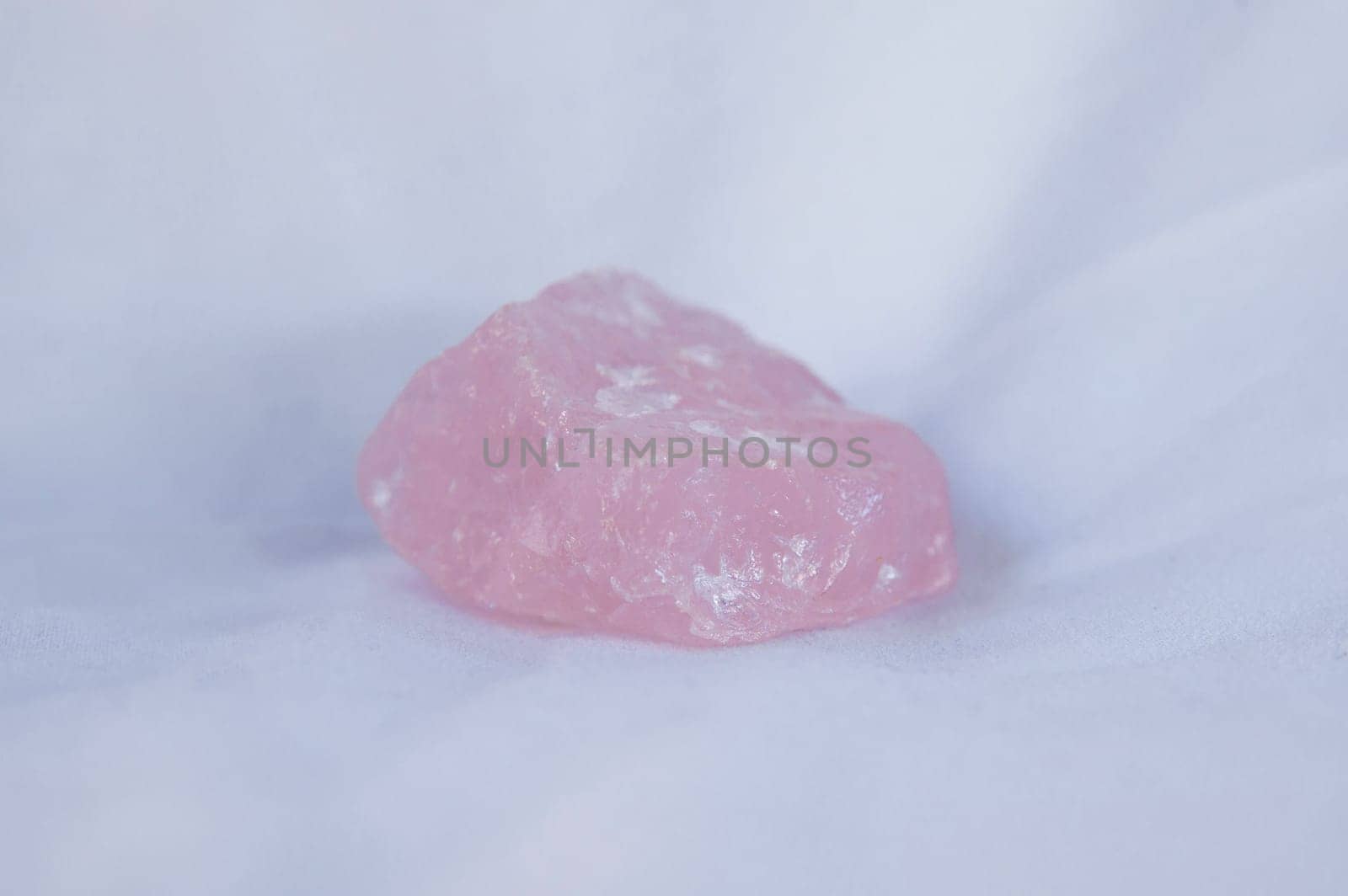 Rose quartz fragment, believed to have beneficial health properties. Isolated over white fabric cloth