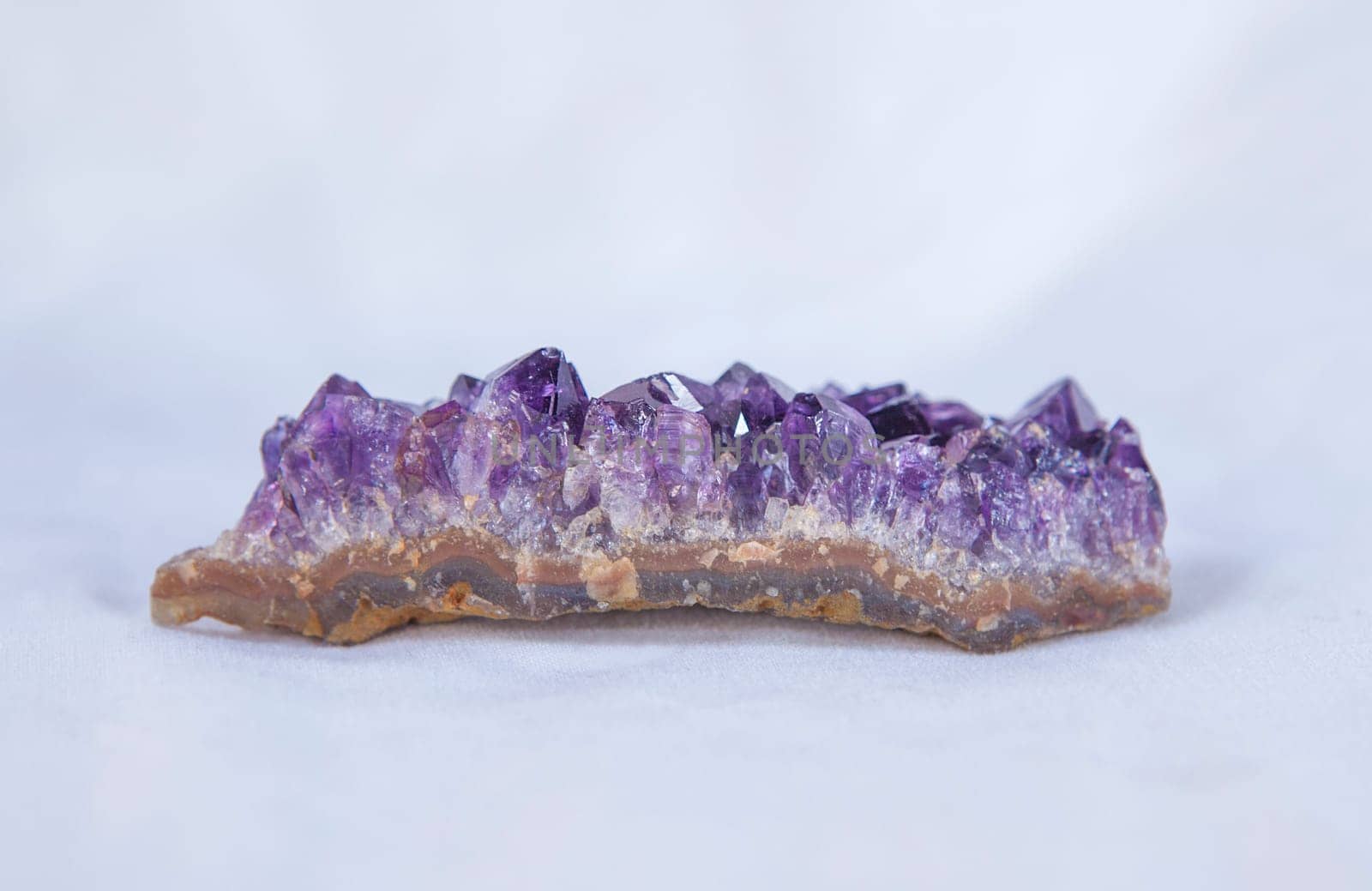 Amethyst geode piece. Isolated over white fabric cloth
