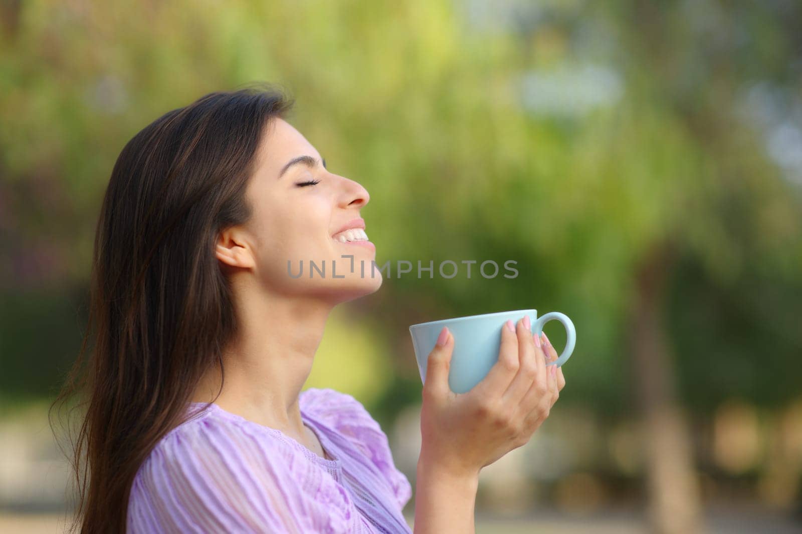 Profile of a happy woman drinking and breathing in a park