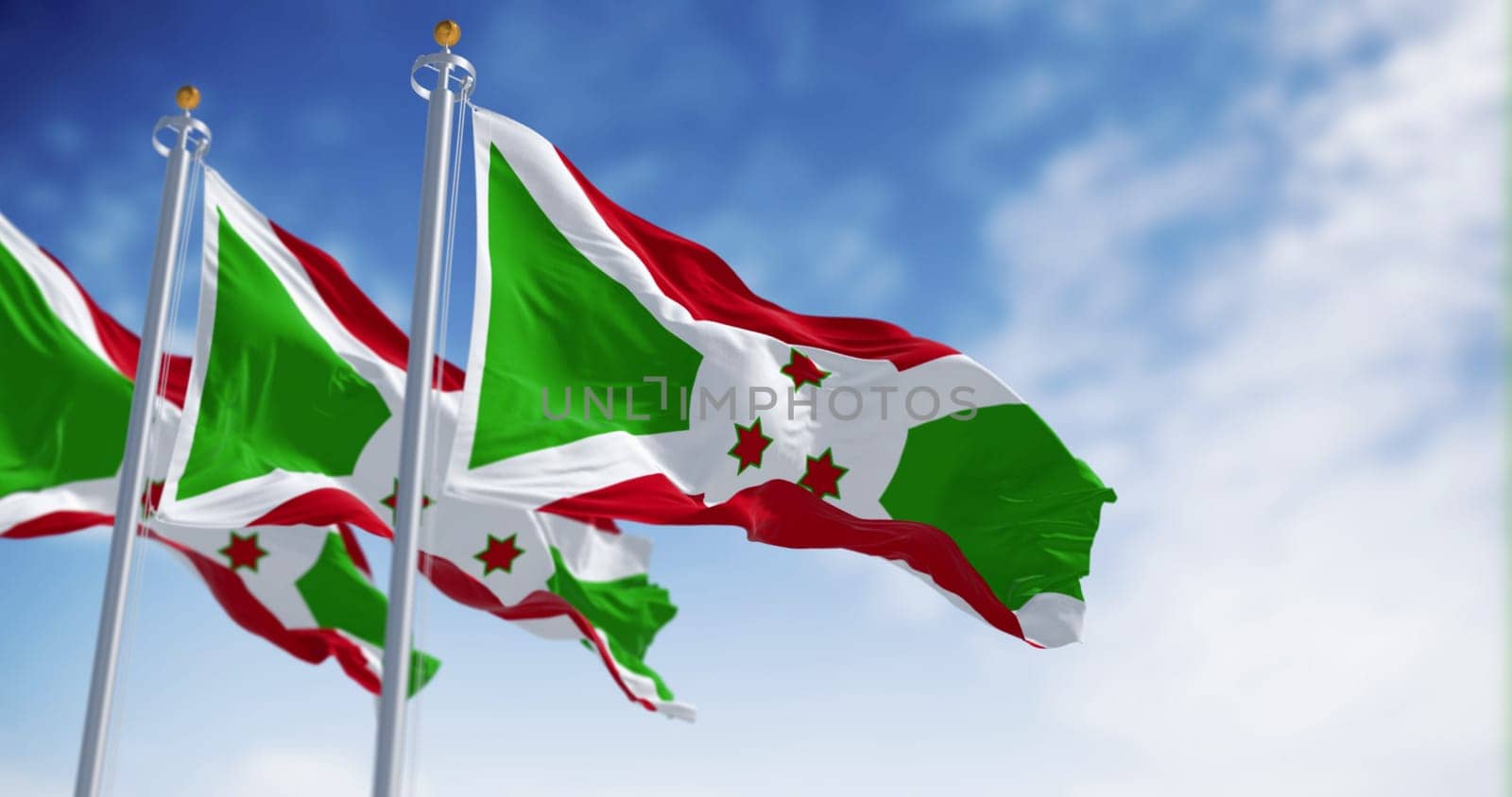 National flags of Burundi waving on a clear day. White diagonal cross dividing into red and green sections, three green stars in the center. 3d illustration render. Fluttering fabric. Selective focus