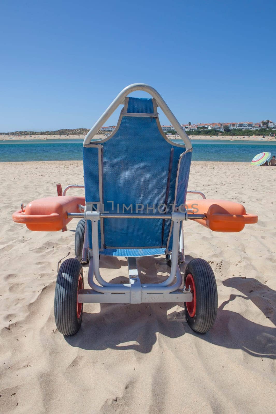 Blue beach wheelchair on sand ready to use. Accessible tourism concept
