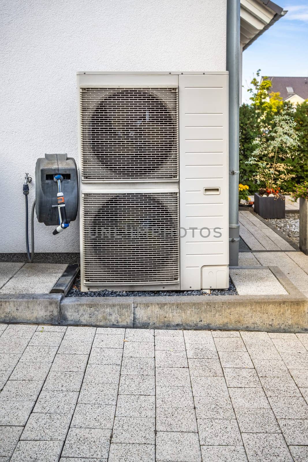 Two air source heat pumps installed outside of modern family house, green renewable energy concept of heat pump