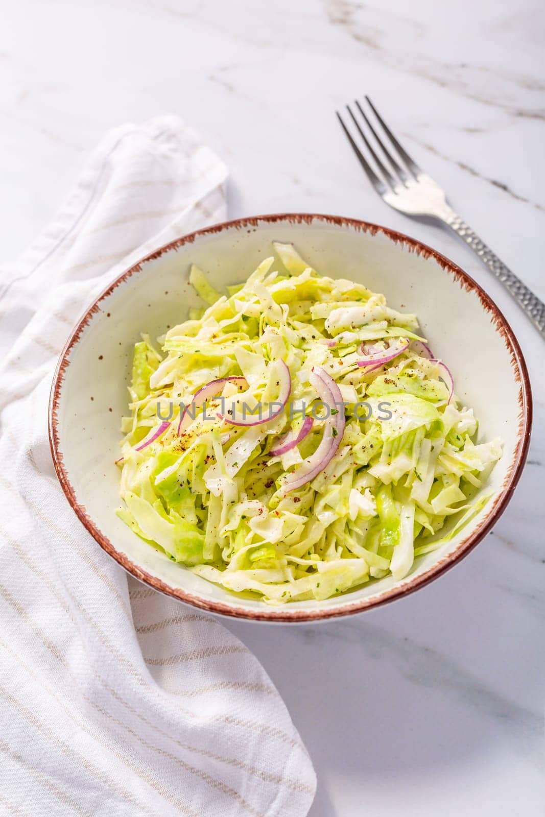 Vegan coleslaw salad made of freshly shredded white cabbage with red onions