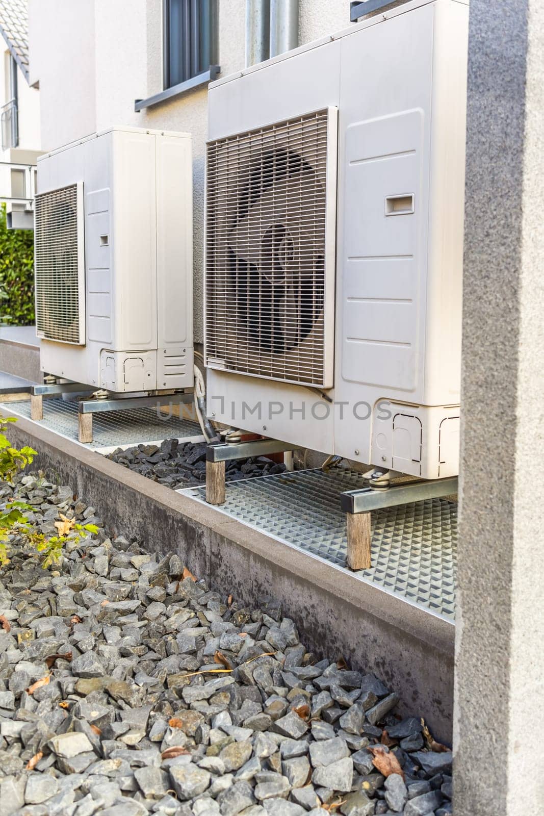 Two air source heat pumps installed outside of modern family house, green renewable energy concept of heat pump