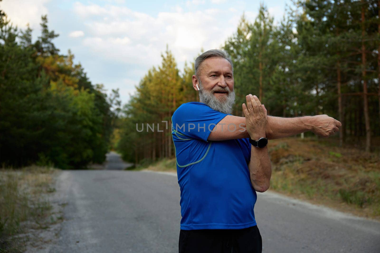 Happy retired sportsman stretching arms before running race start. Warm up workout and cardio exercise preparation