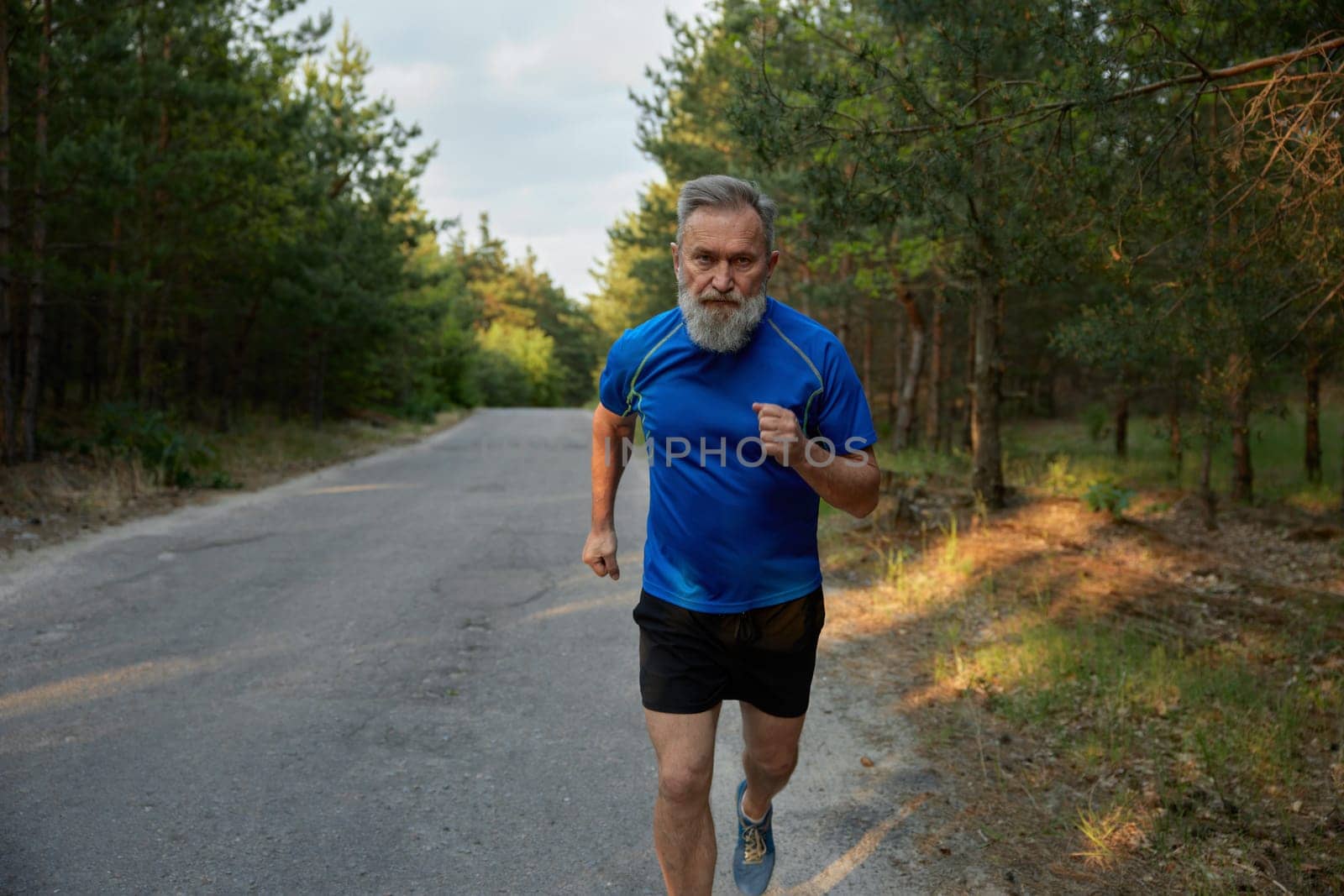 Senior man running outside among countryside road. Healthy lifestyle and physical activity for wellness on retirement