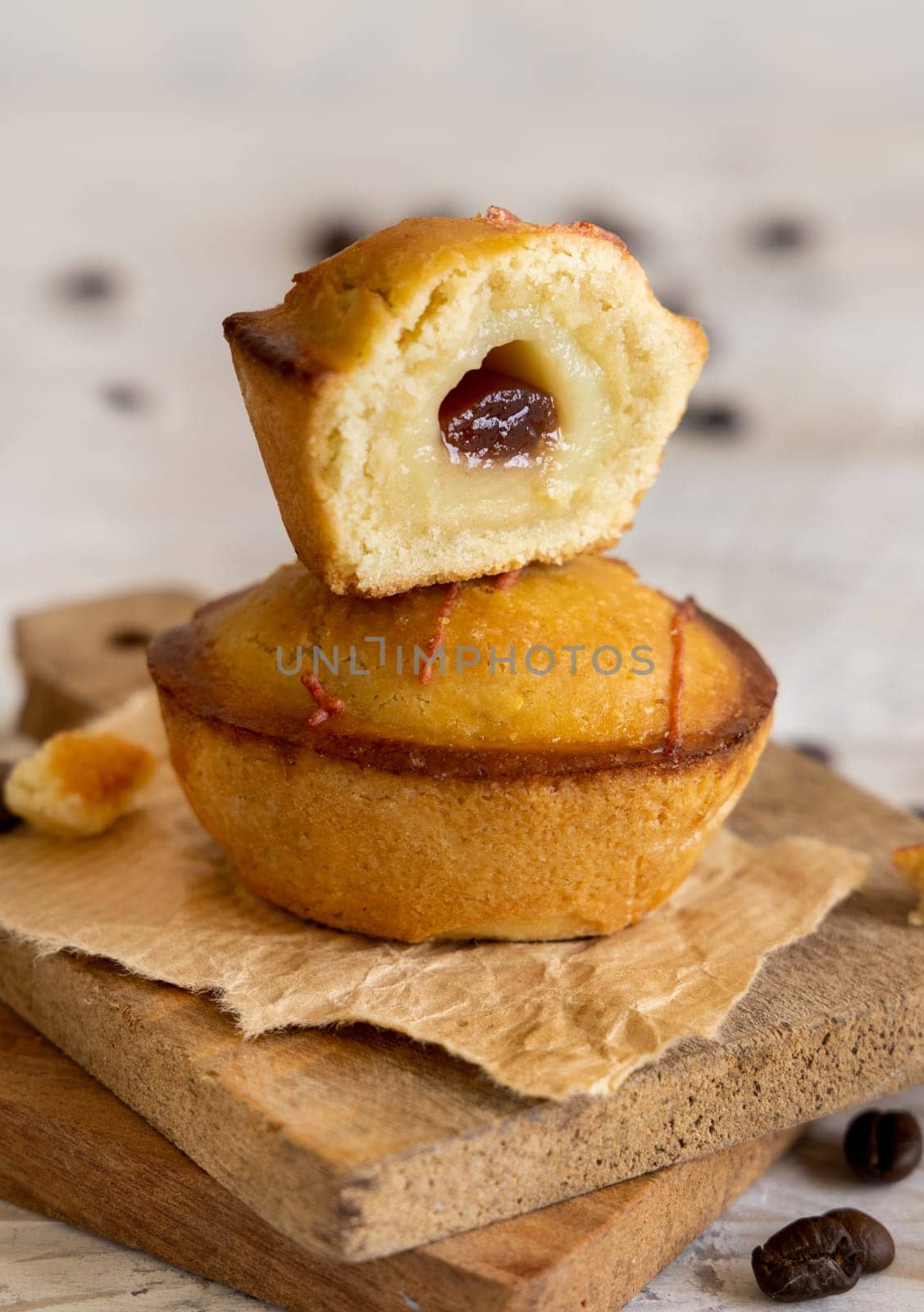 Pasticciotto leccese pastry filled with egg custard cream and sour cherry jam. Whole and half pasticiotties on a wooden tray served for typical apulian breakfast, close up. Table decorated with coffee beans