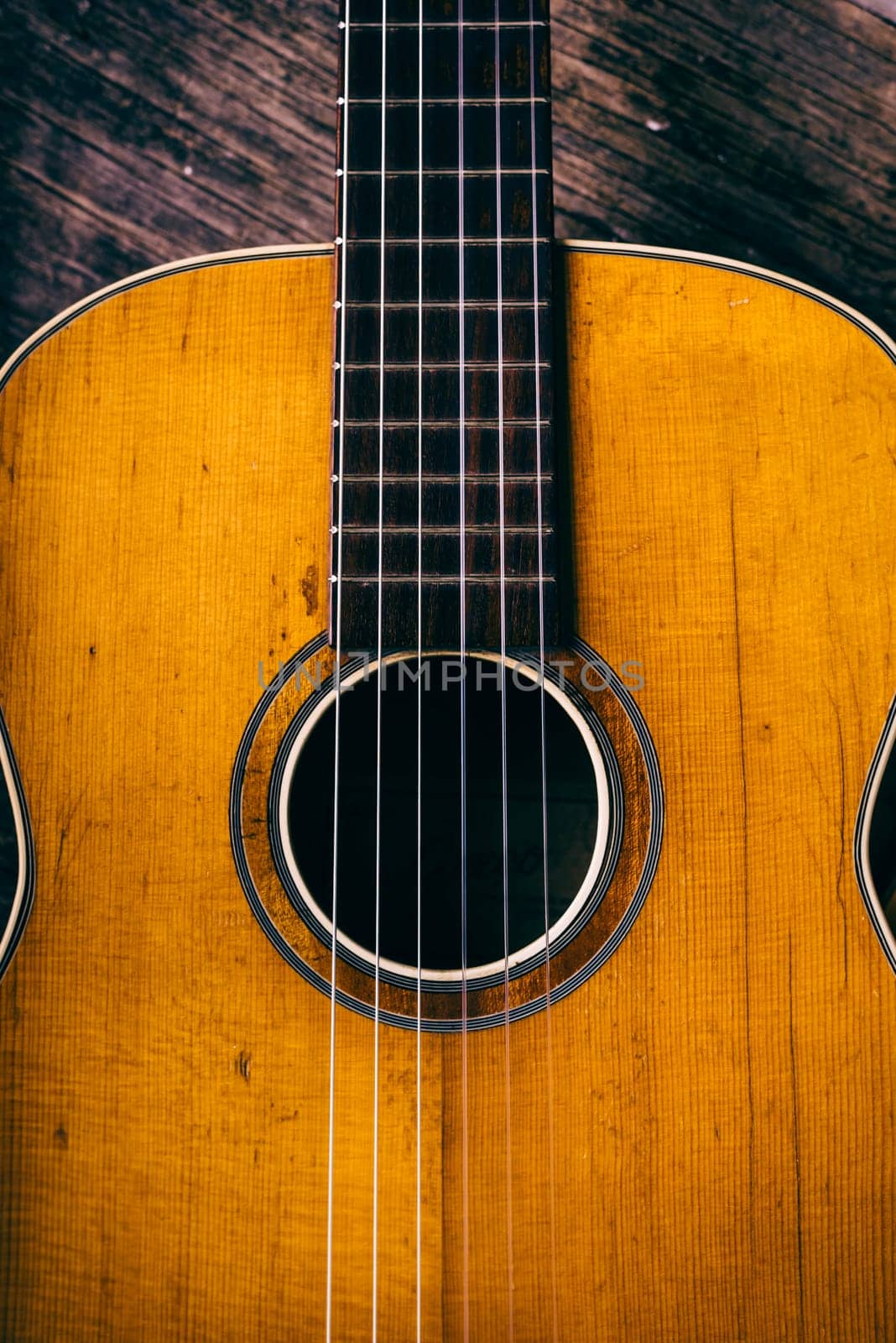 Closeup of wooden acoustic guitar from above. Music vintage background.