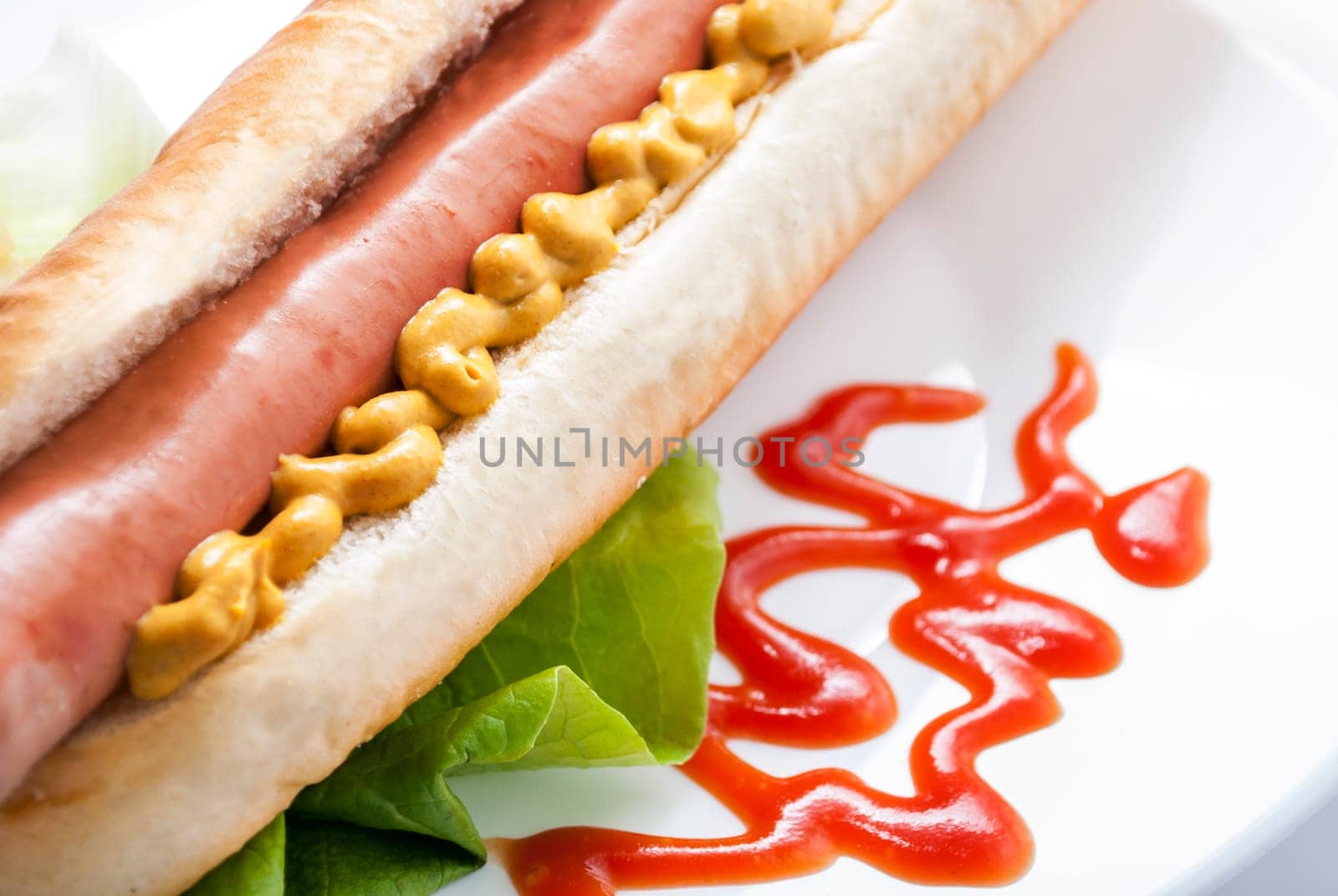 Hot dog with mustard and ketchup on white plate. Closeup of american hotdog. Fast food restaurant menu.