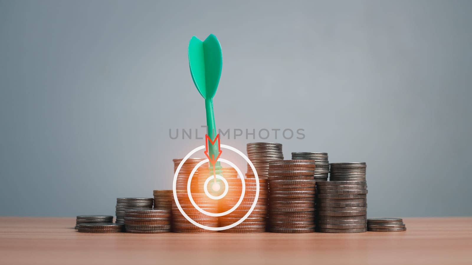 The green arrow hits the target in the center of a row of coins on the wooden floor. Concepts of finance, savings and investment. Business growth concept, finance goals concept.