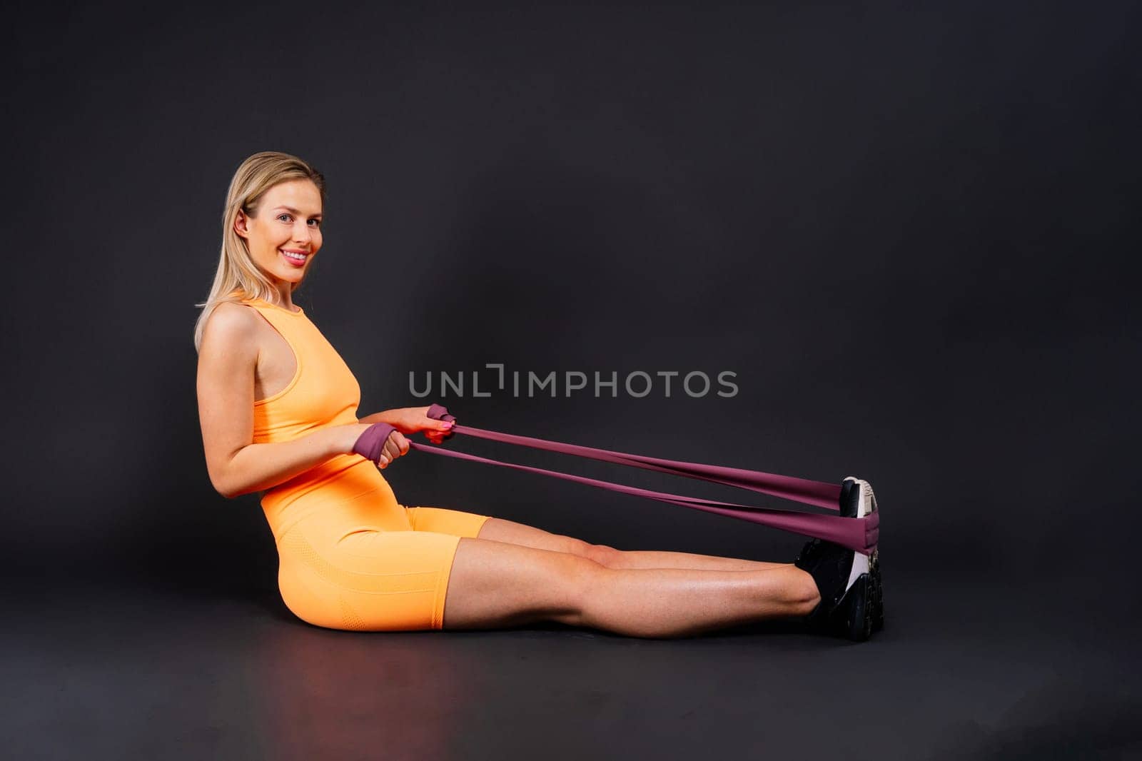 Blond woman with jump rope in a studio, yellow red and dark background
