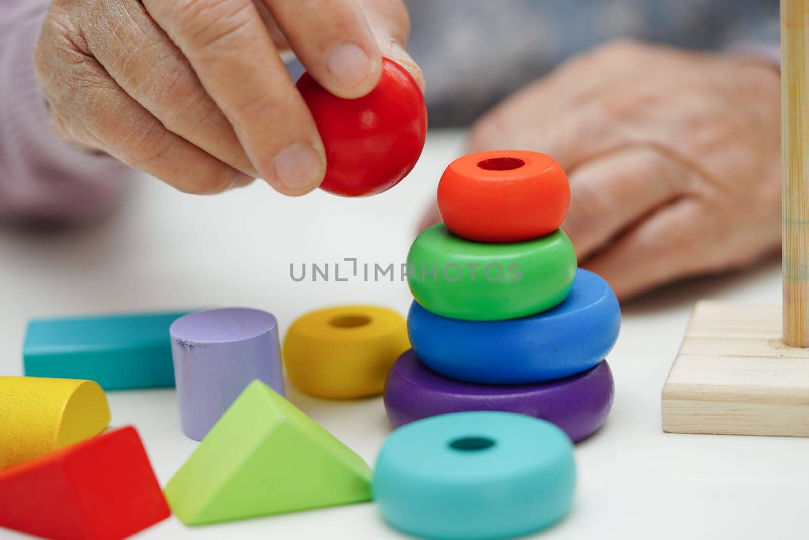 Asian elderly woman playing puzzles game to practice brain training for dementia prevention, Alzheimer disease.