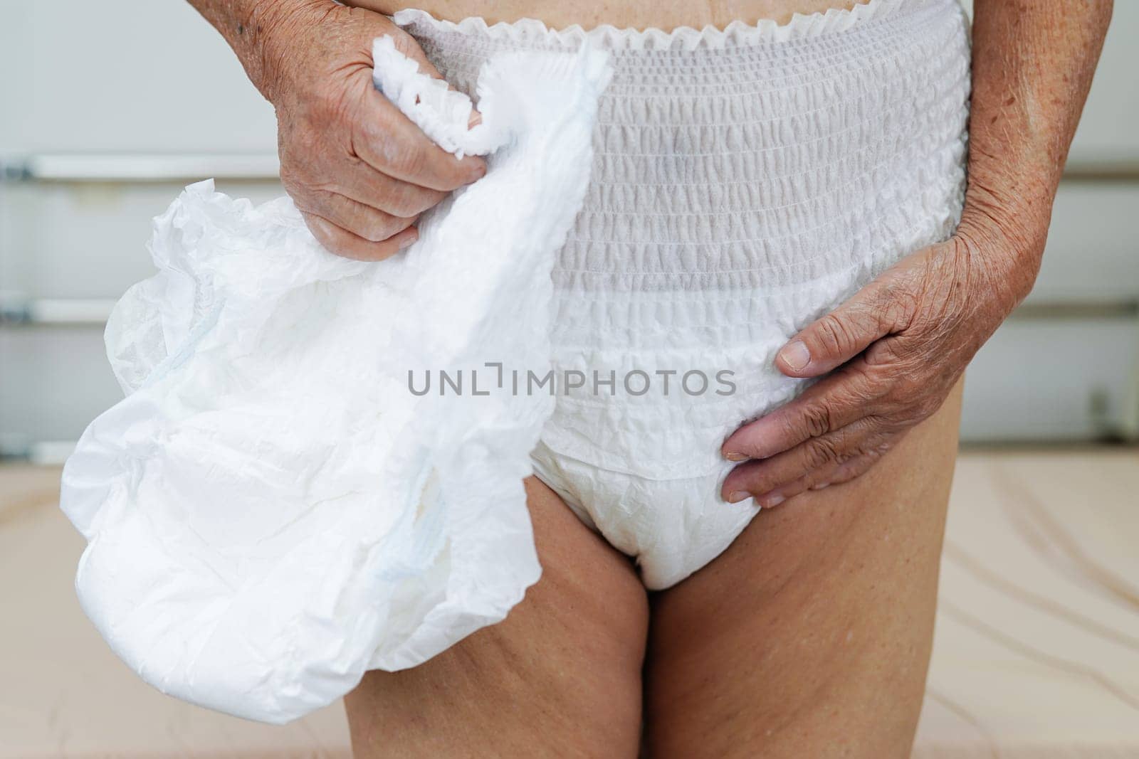 Asian elder senior woman patient wearing adult incontinence diaper pad in hospital.