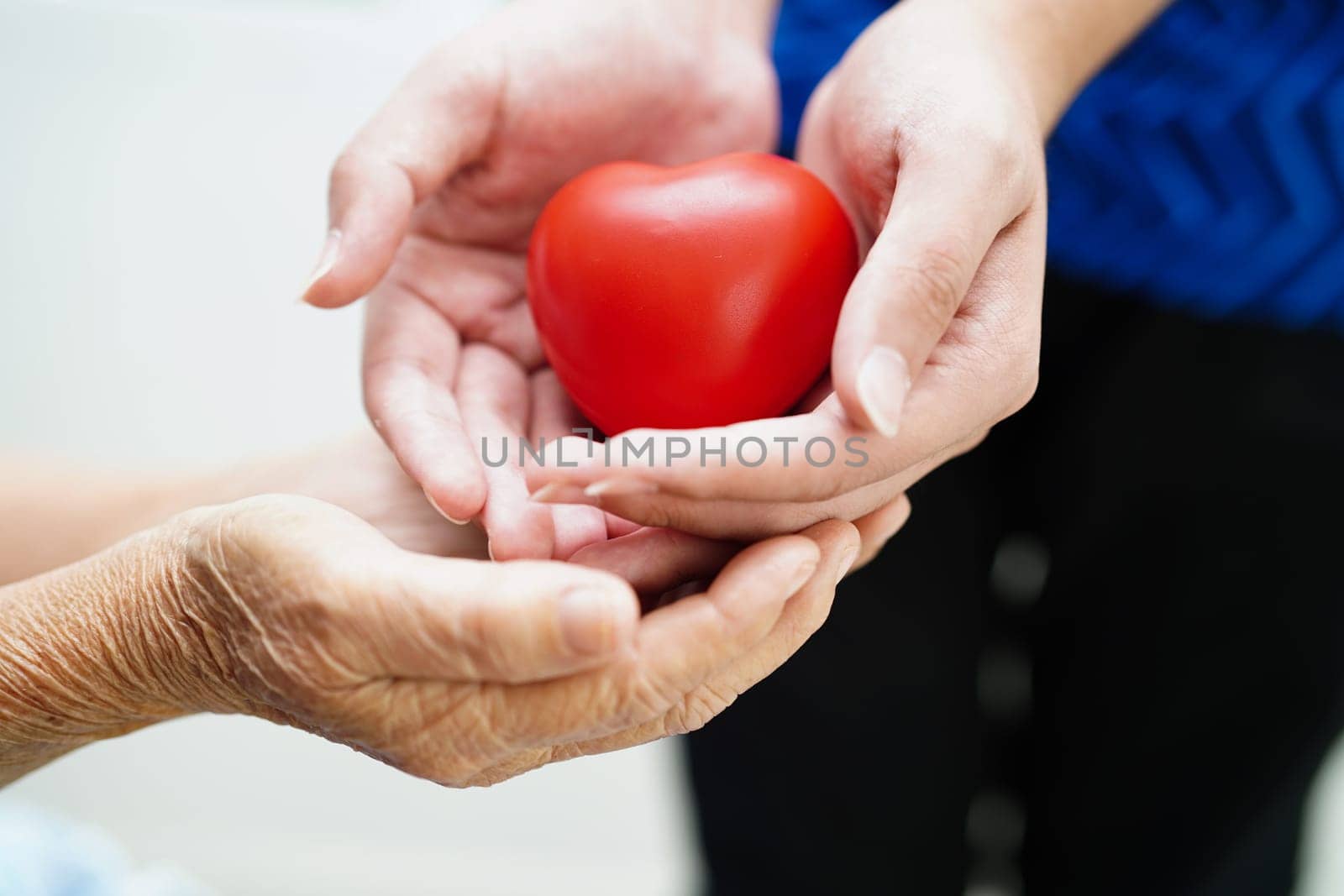 Asian young boy give red heart to old grandmother with love and care.
