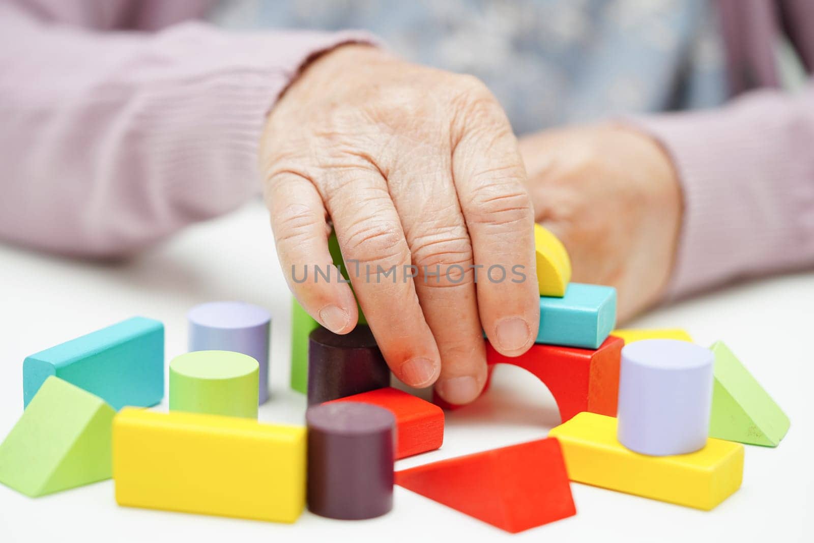 Asian elderly woman playing puzzles game to practice brain training for dementia prevention, Alzheimer disease.