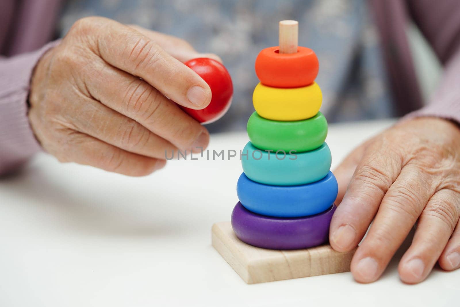 Asian elderly woman playing puzzles game to practice brain training for dementia prevention, Alzheimer disease.