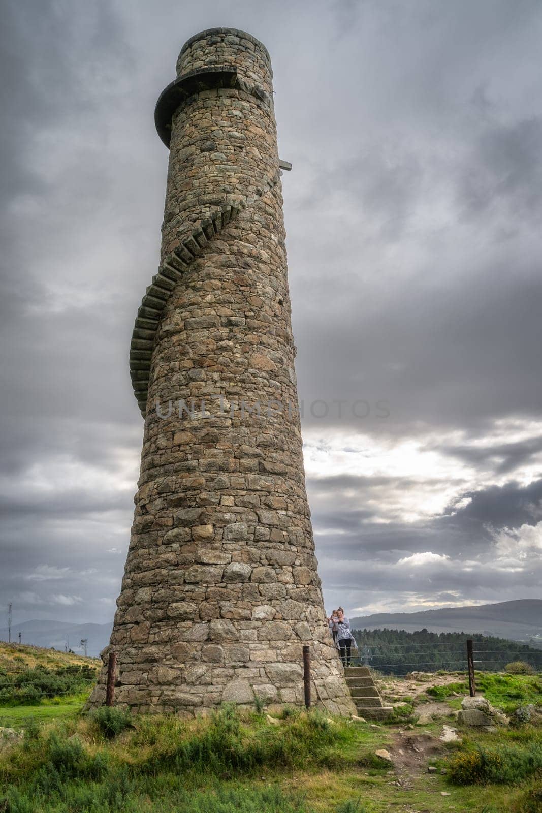 Mother and daughter standing on the external spiral stairs of old and abandoned stone chimney in Lead Mines, Wicklow Mountains, Ireland