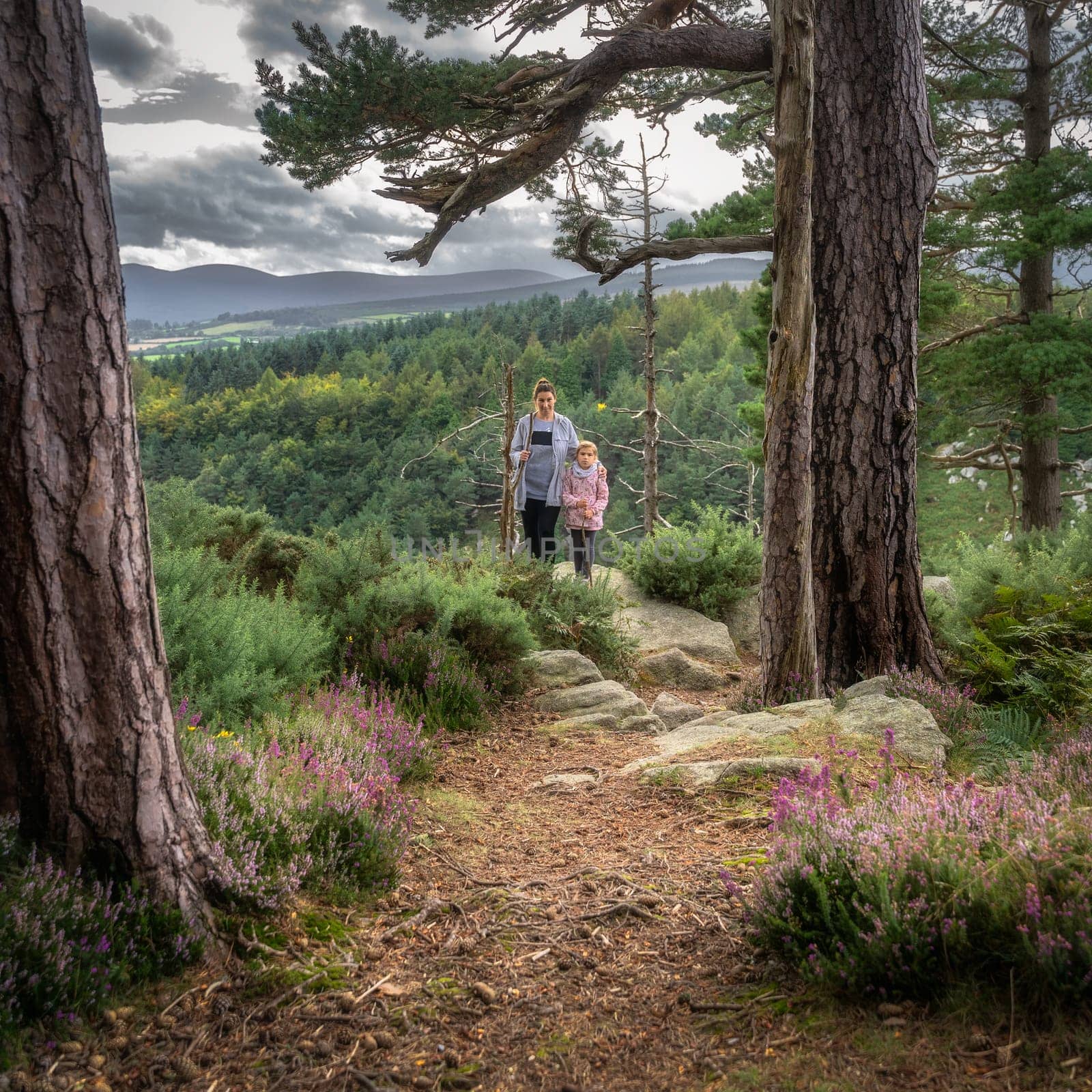 Mother and daughter standing on a viewpoint in Lead mines, with a view on a valley and pine forest. Family hike in Wicklow Mountains, Ireland