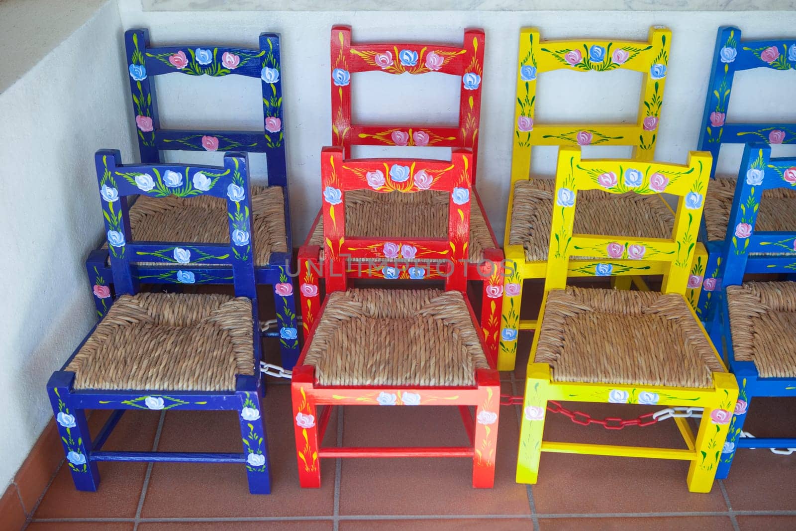 Vila Nova, Portugal - Jul 26th, 2023: Colorful children chairs. Seat made of rush leaves. Alentejo crafts