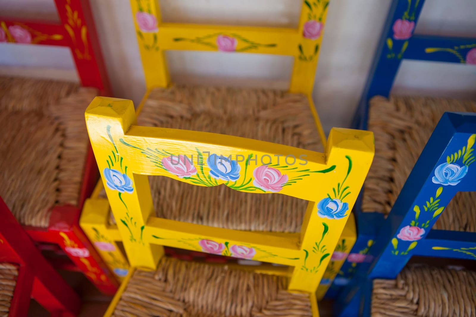 Vila Nova, Portugal - Jul 26th, 2023: Colorful children chairs. Seat made of rush leaves. Alentejo crafts