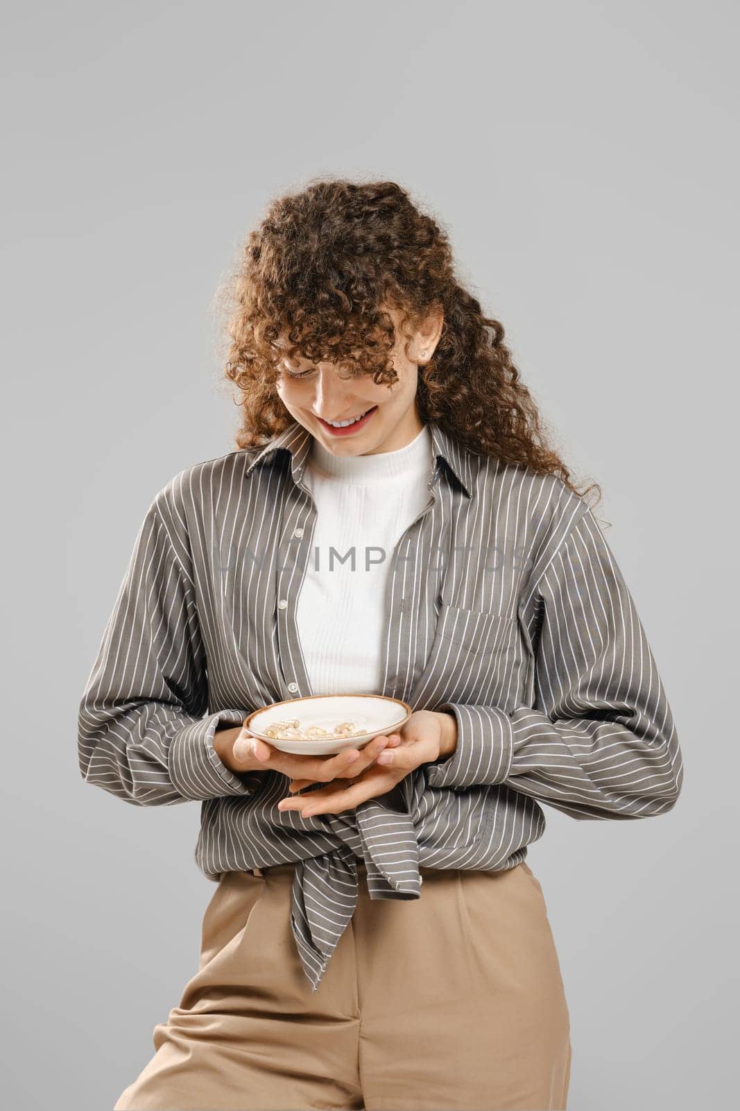 Smiling woman holds a plate full of pills in her hands