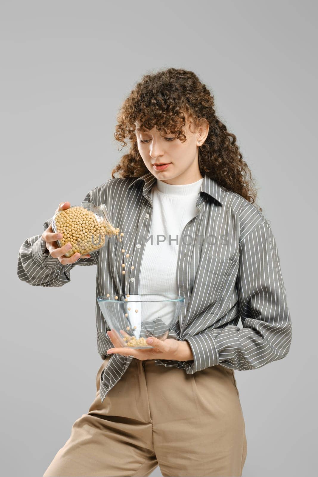 Slender woman pours dry chickpeas from bowl to bowl