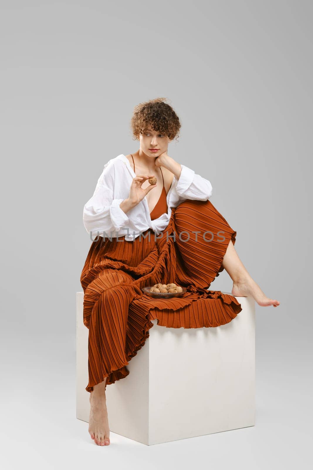Barefoot woman took a walnut from a plate and looks at it