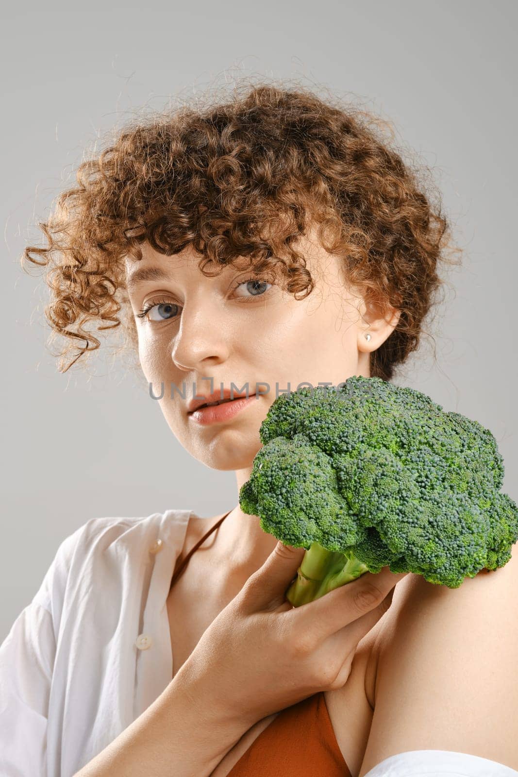 Cute young woman holds broccoli in hand. Concept of healthy eating.