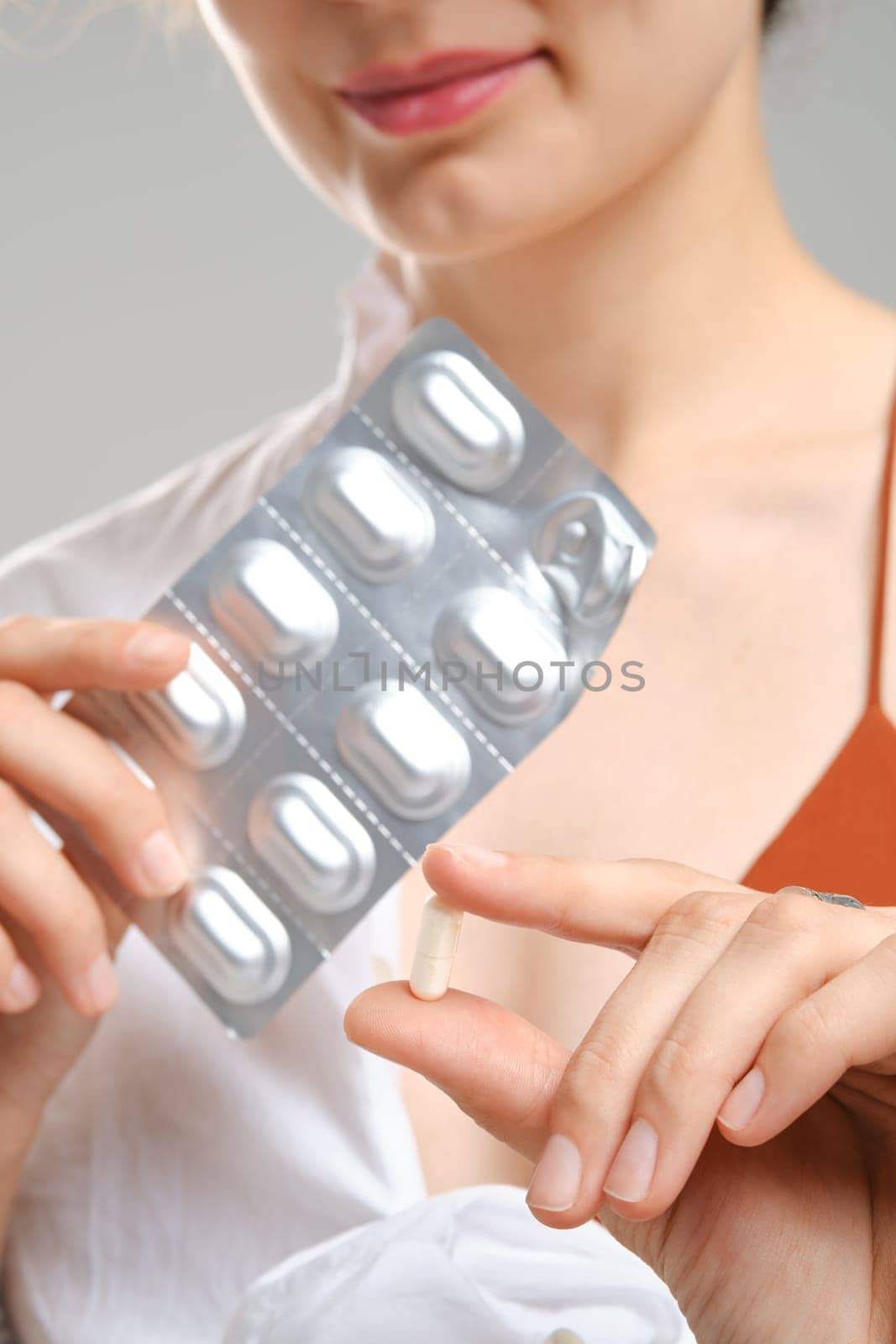 Close up view of fingers holding a pill in front of the package