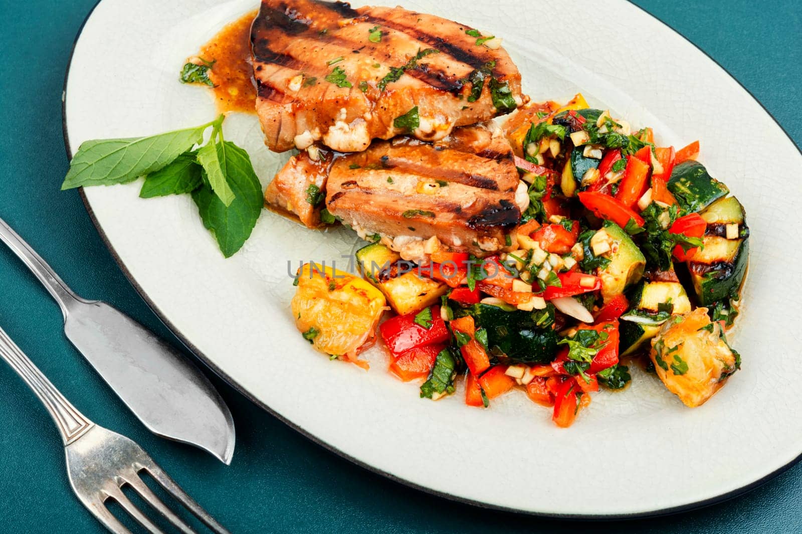 Cooked tuna steak with vegetables on a plate. Seafood.