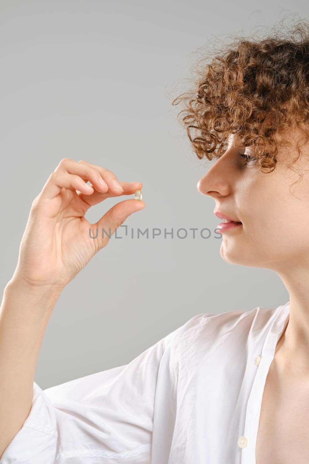Woman holds pill or vitamin in hand