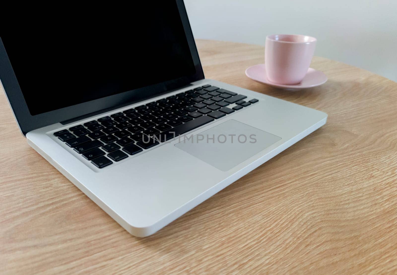 Living room table with laptop and pink blush mug. Domestic workspace concept