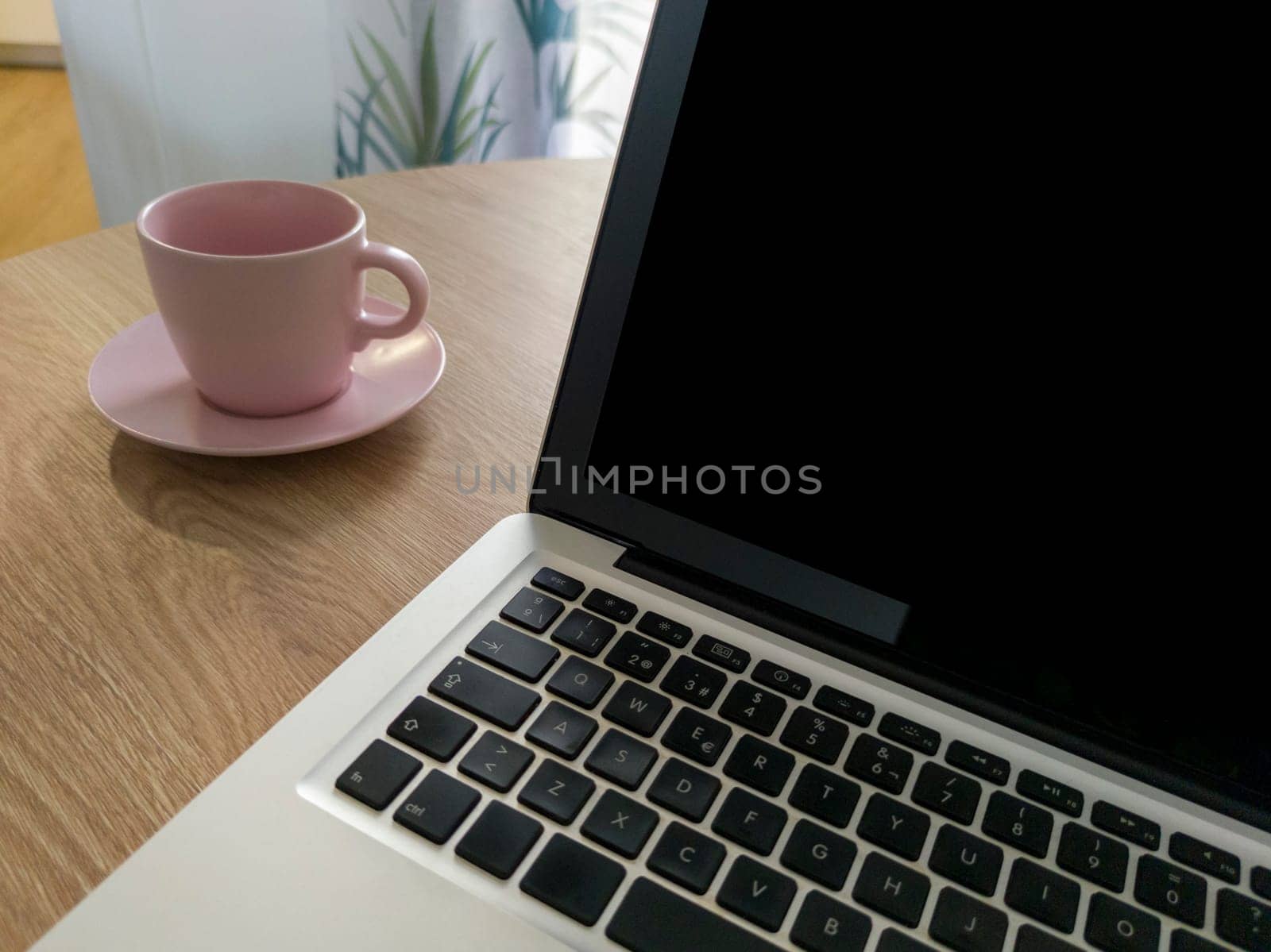 Living room table with laptop and pink blush mug. Domestic workspace concept