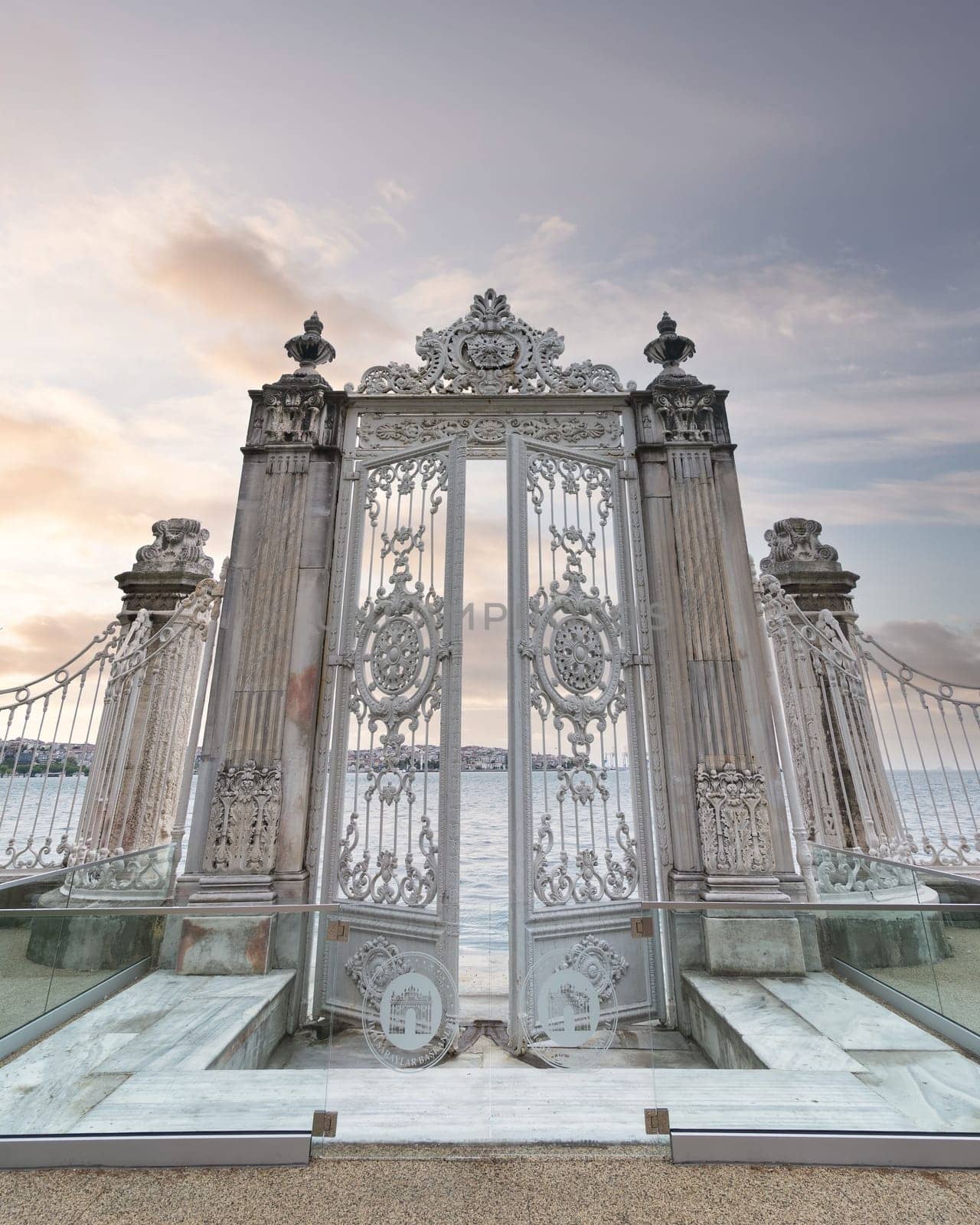 Pair of elaborately decorated white painted metal gates leading to the opulent Dolmabahce Palace in Istanbul, Turkey, and offering stunning views of the Bosphorus Strait