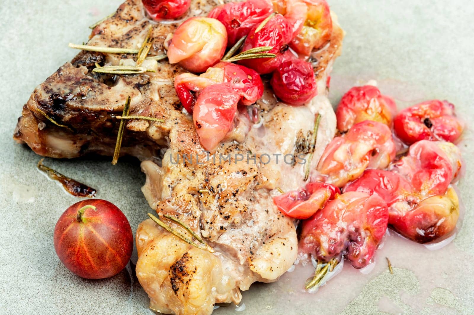 Delicious grilled beef steak with gooseberry on rustic wooden table.