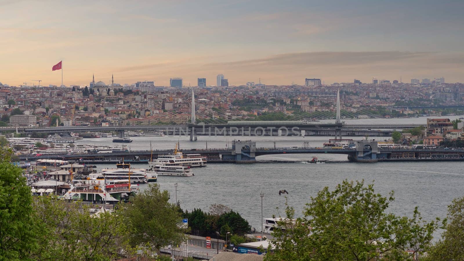 Panoramic skyline of European side of Istanbul with ferry boats sailing in Bosphorus strait, overlooking Halic Metro Bridge with clear sky in a spring day before sunset, Istanbul, Turkey